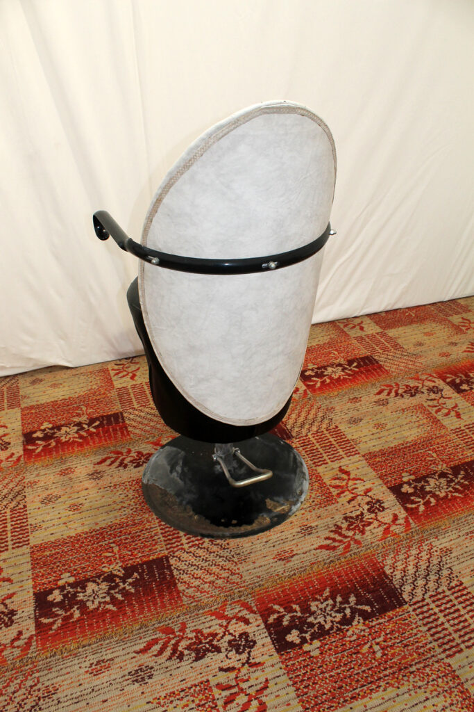 a white hat sitting on top of a black stand.