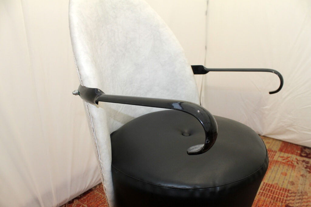 ein schwarzer Stuhl mit einem weißen Surfbrett dahinter.